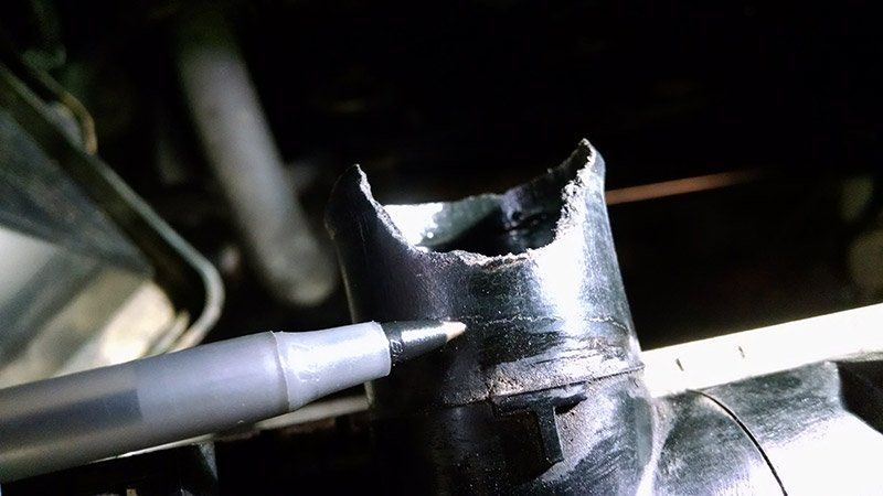 A pen is pointing at a hole in a metal pipe.
