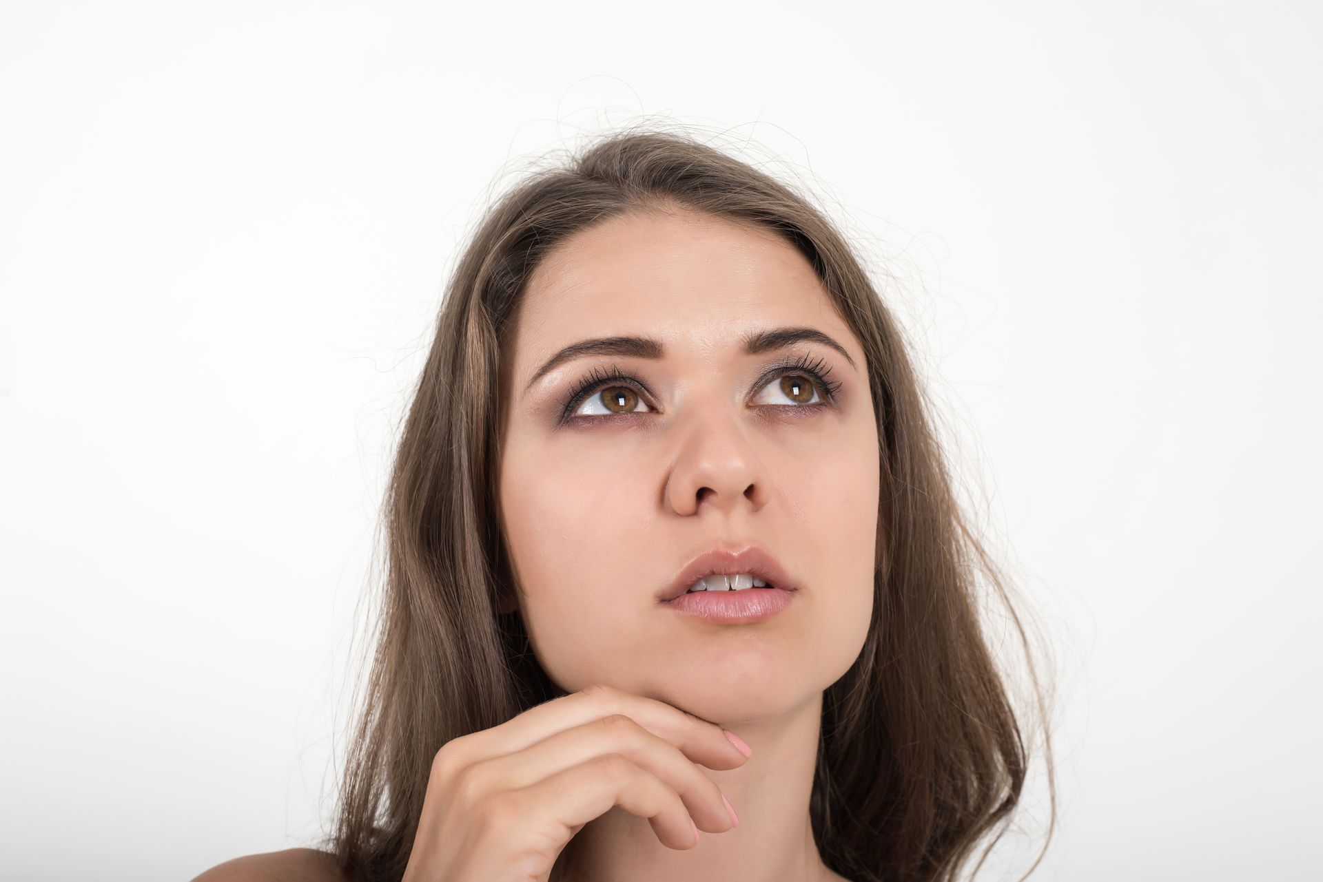 A woman is looking up with her hand on her chin.