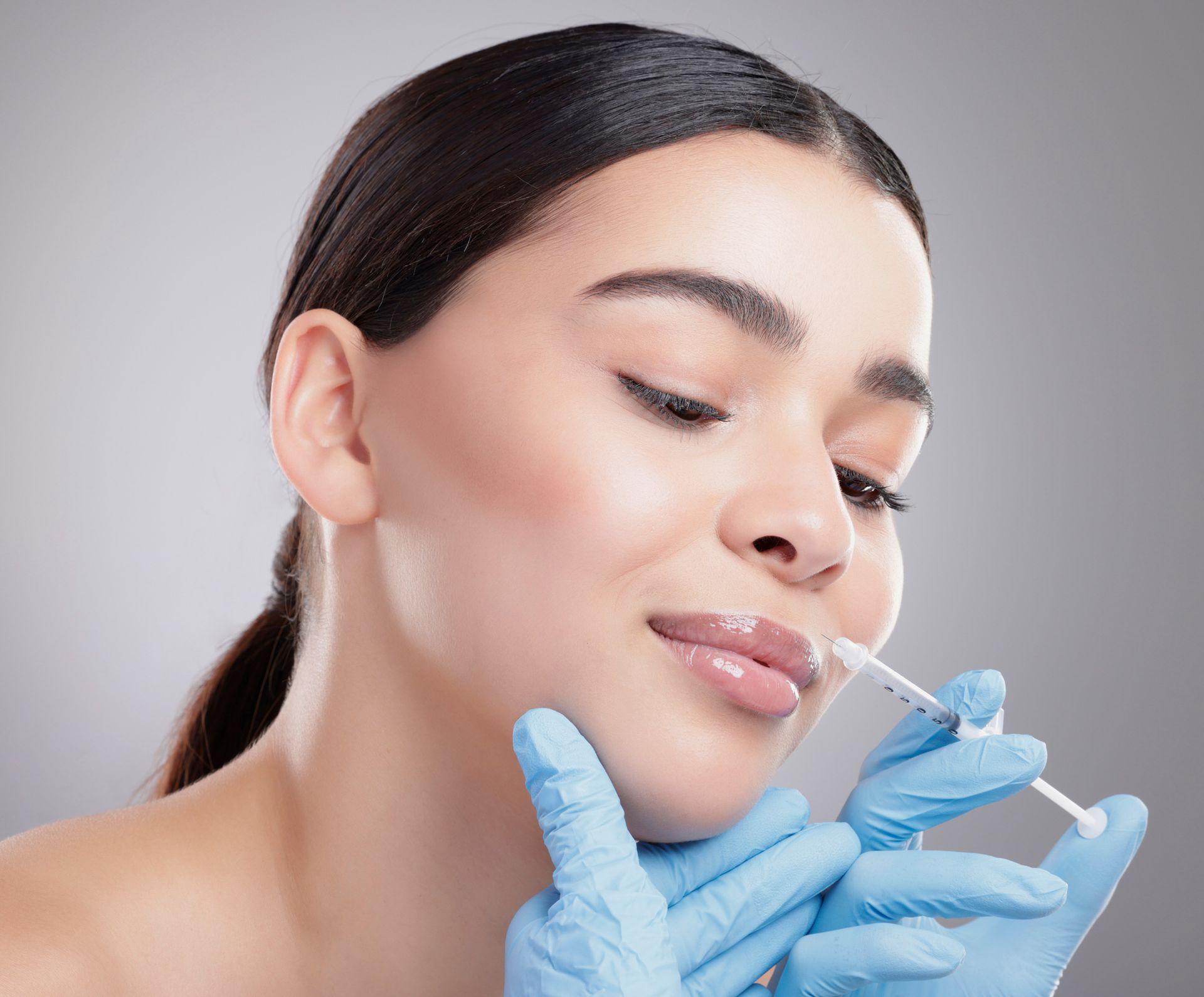 A woman is getting a botox injection in her lips.