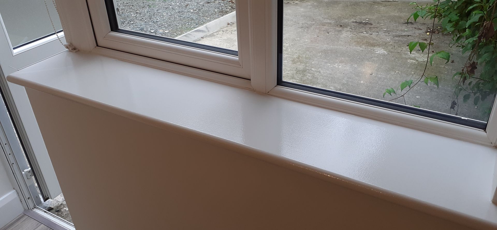 A white window sill with a window in the background.