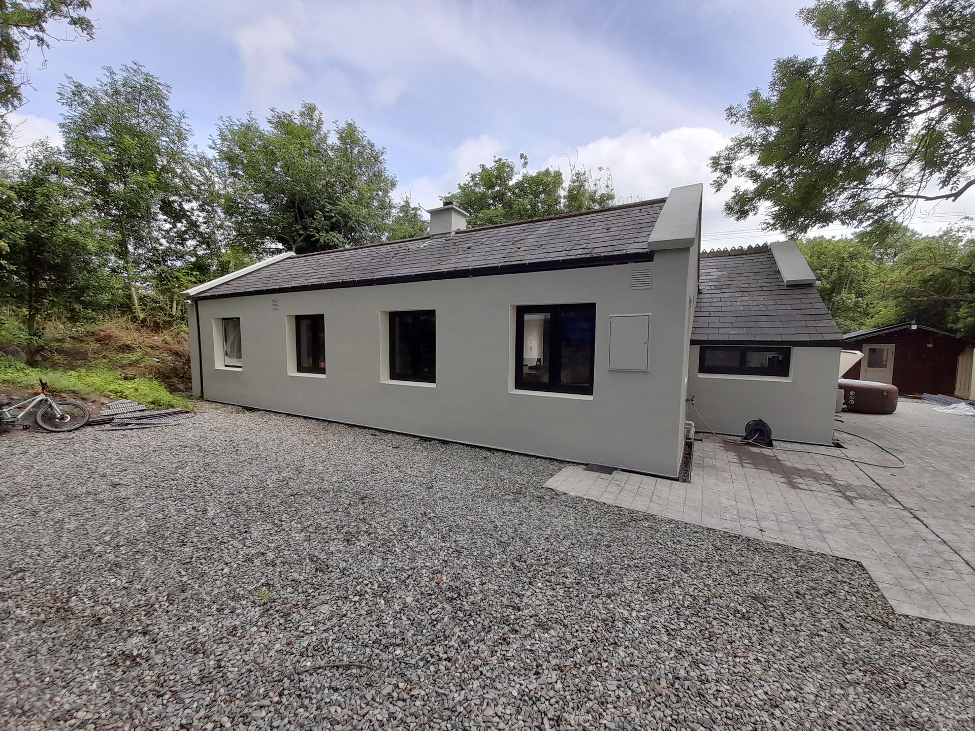 A small white house with a gravel driveway in front of it