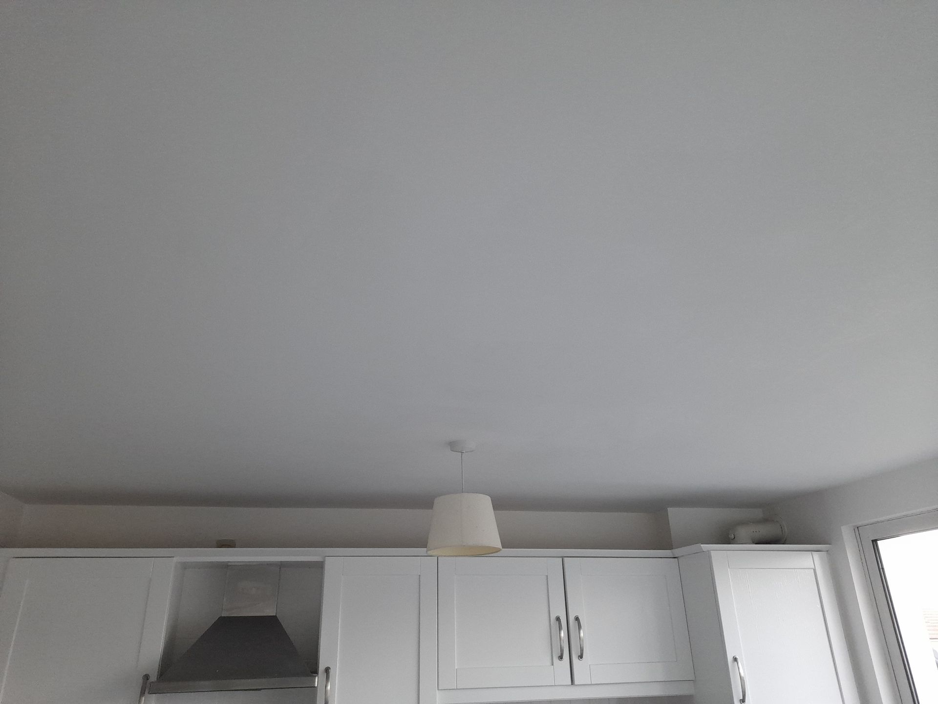 A kitchen with white cabinets and a white ceiling.
