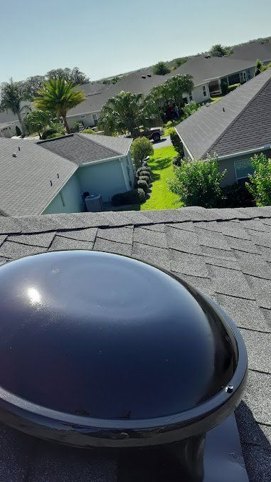 A roof vent on top of a house with a view of a residential area.