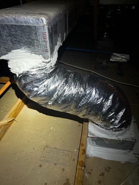 A duct is wrapped in plastic and is sitting on a wooden floor.