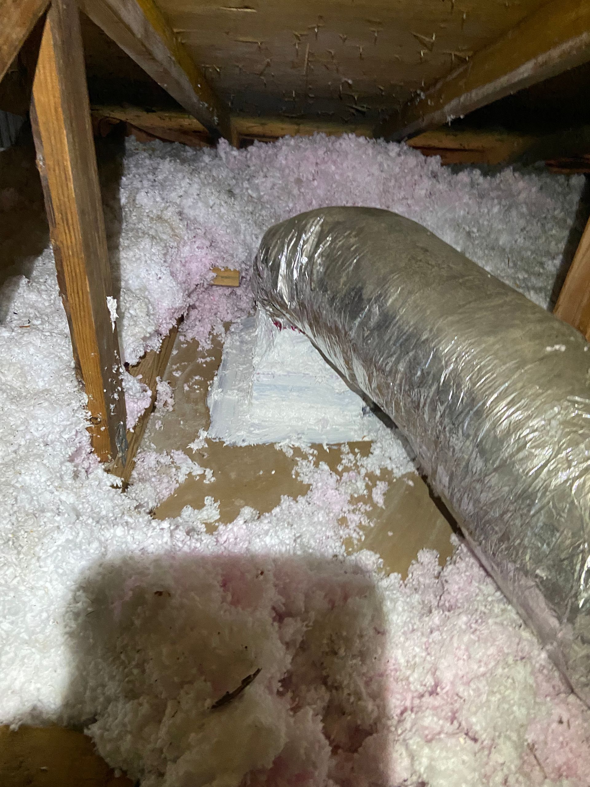 There is a pipe in the attic that is covered in insulation.