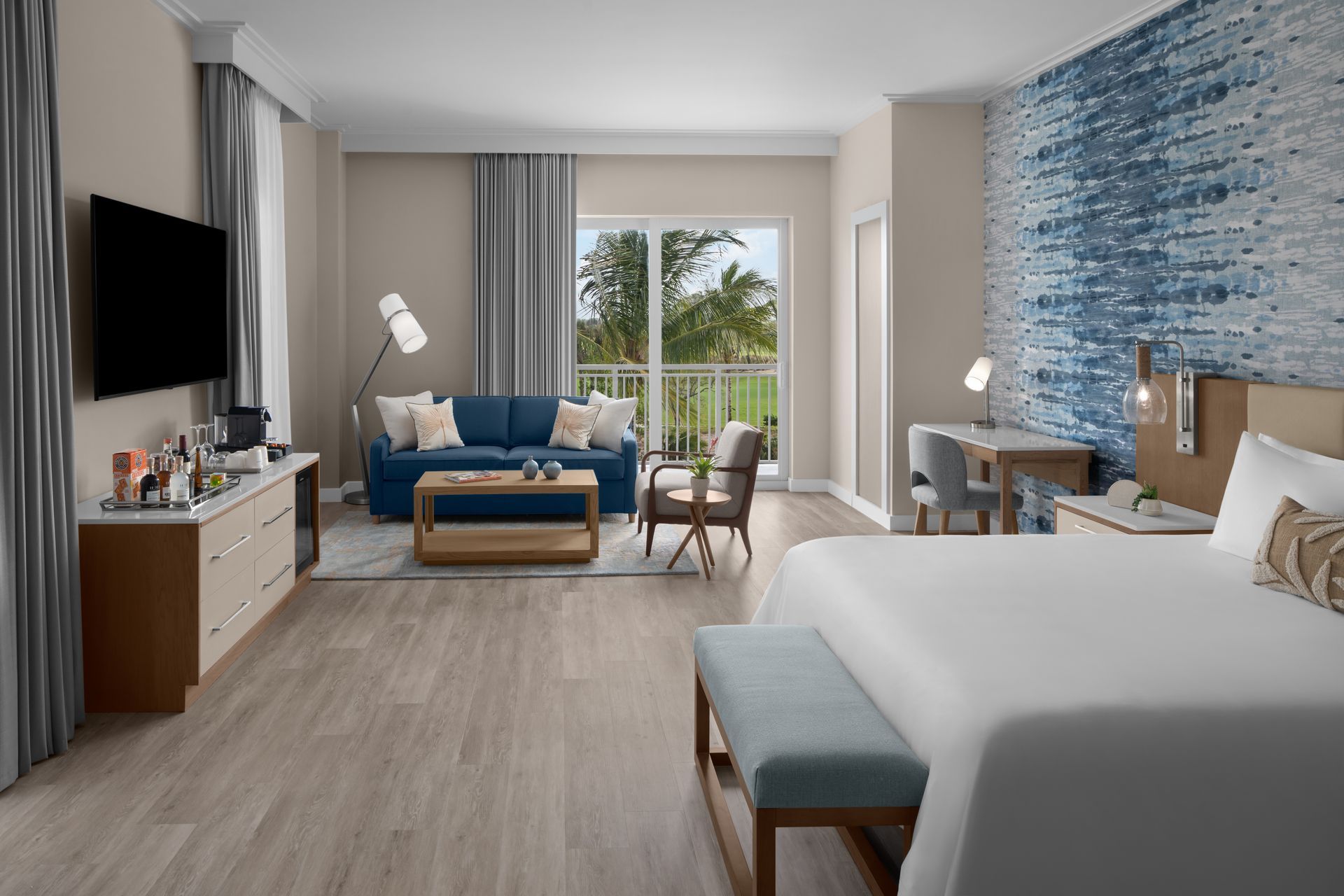 A hotel room with a king size bed , television , couch and chairs.