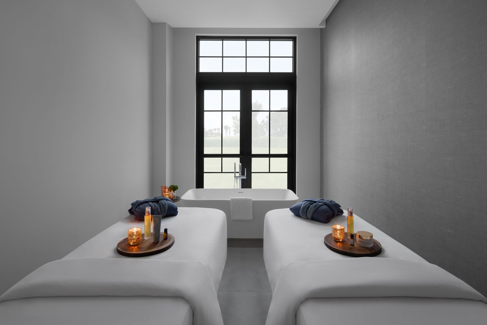 A spa room with two beds and a bathtub.