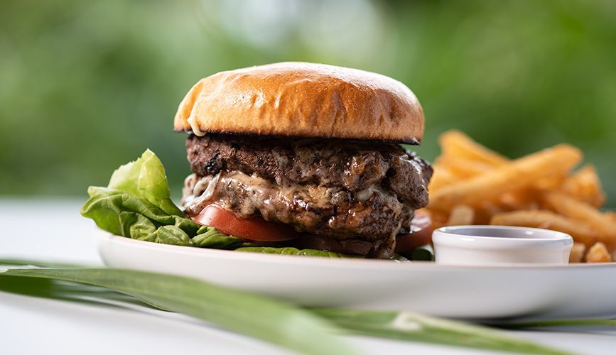 Our Story A hamburger and french fries on a white plate on a table.
