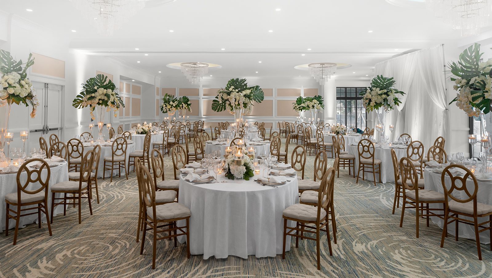 A large room with tables and chairs set up for a wedding reception.