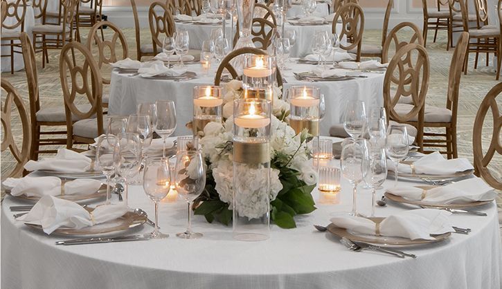 A table set for a wedding reception with candles and flowers on it.