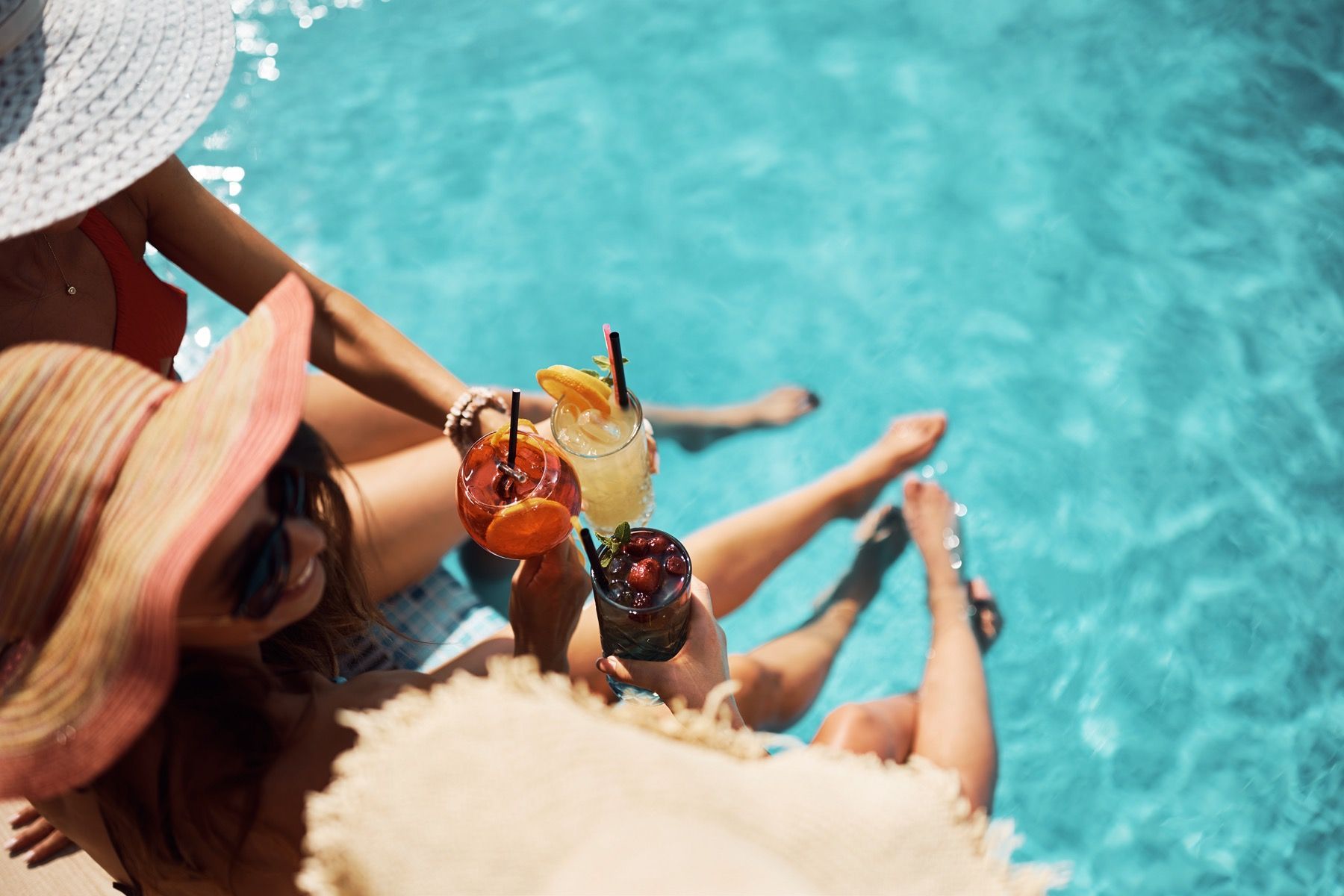 A group of women are sitting in a swimming pool holding drinks.