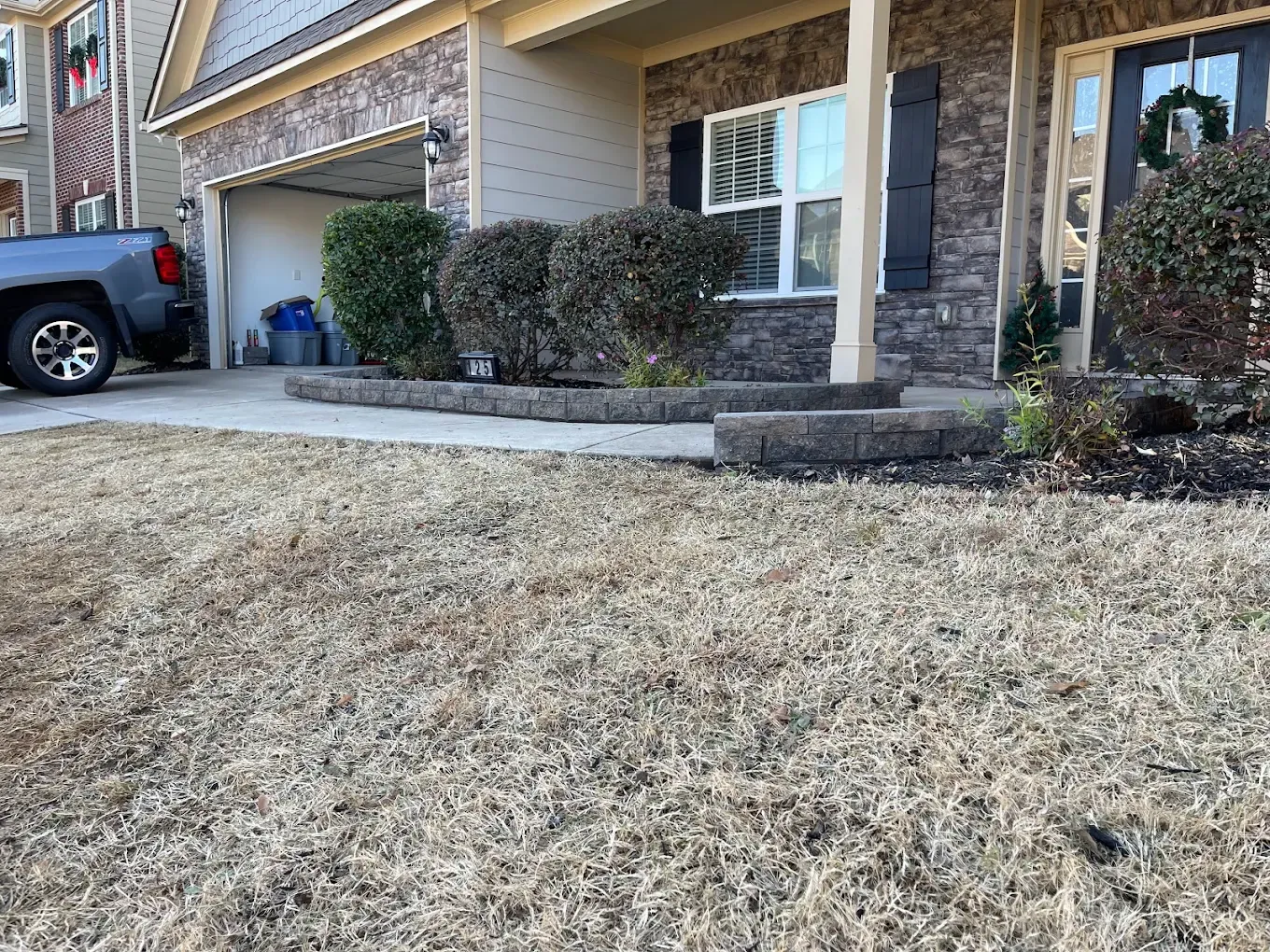 A house with a driveway and dry brown grass in the front yard.