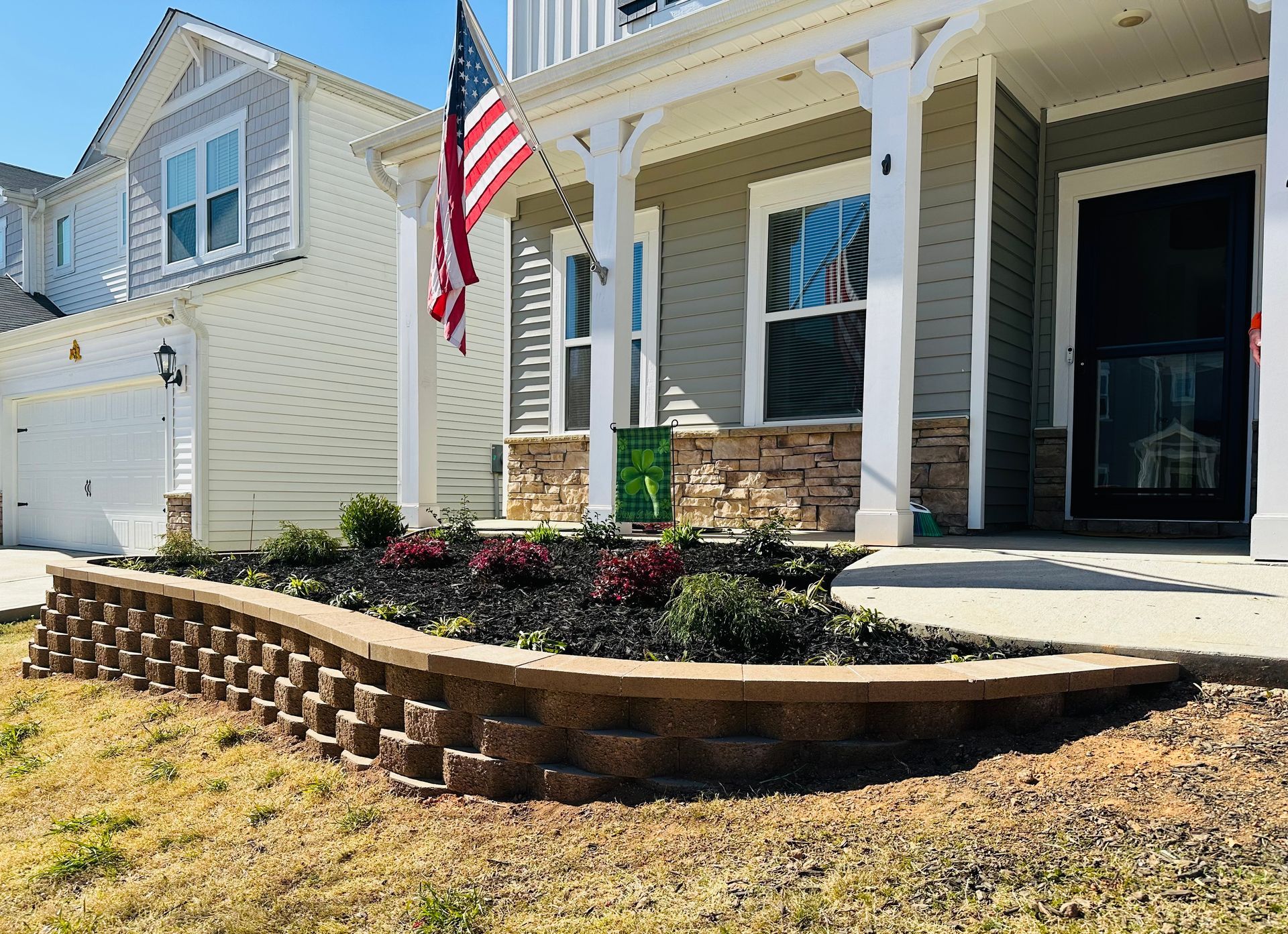 House exterior with landscaped flower bed and American flag.