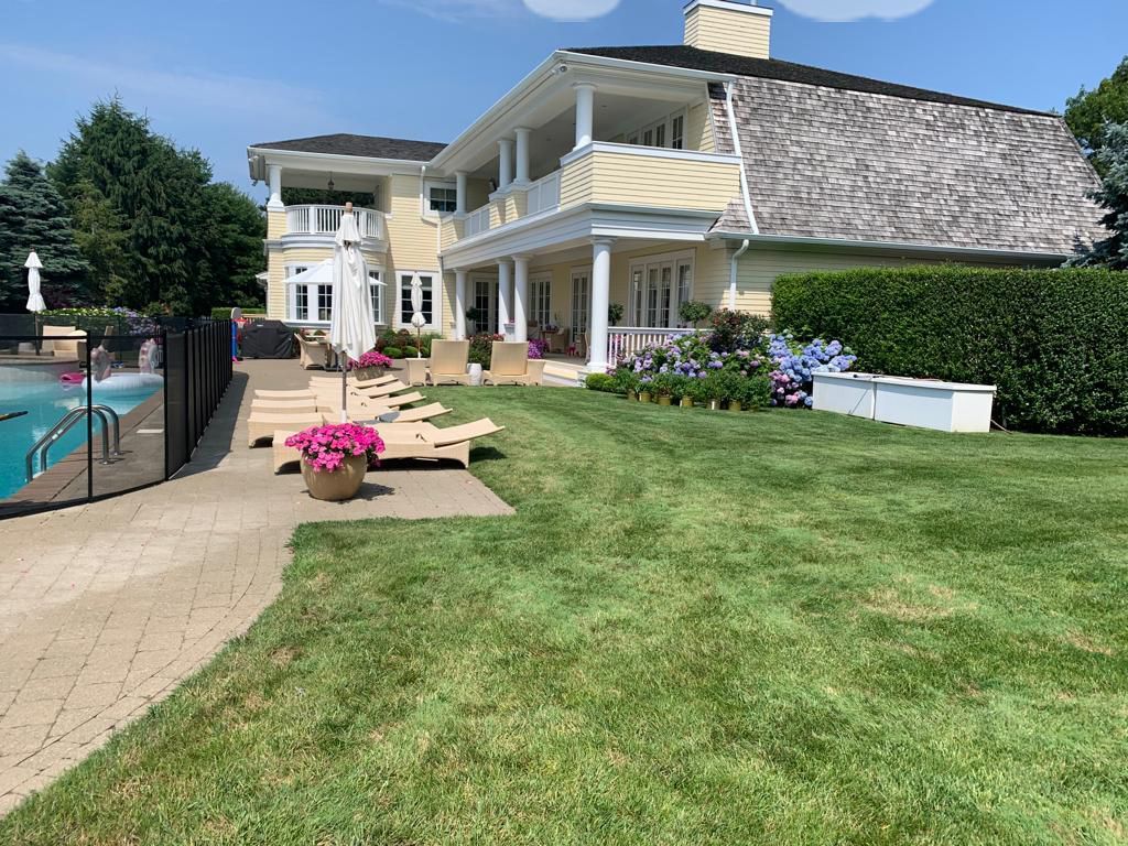 Yellow house with pool, lawn, and lounge chairs; sunny day.