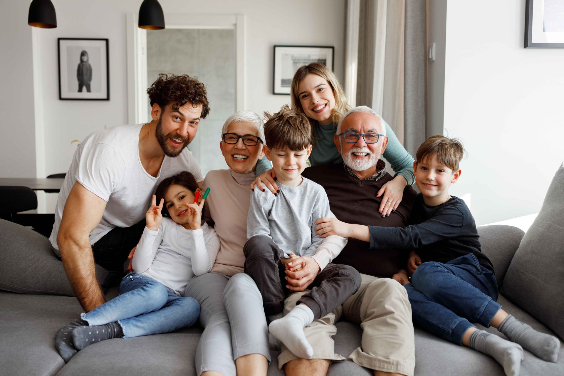 Multi-generational group smiling together on a couch in a living room.