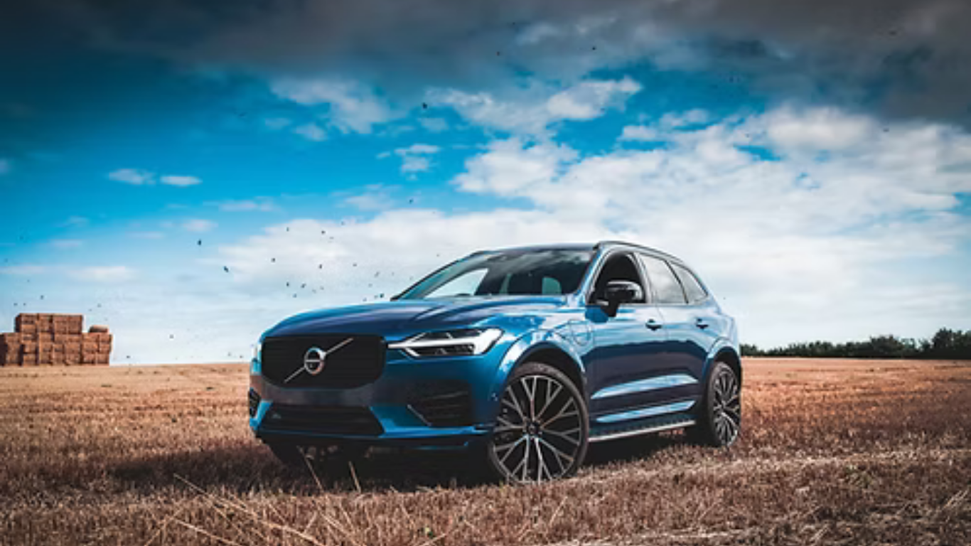 Blue Volvo SUV parked in a dry field under a cloudy sky