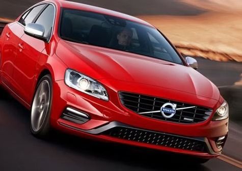Red Volvo sedan driving on a road with a blurred background