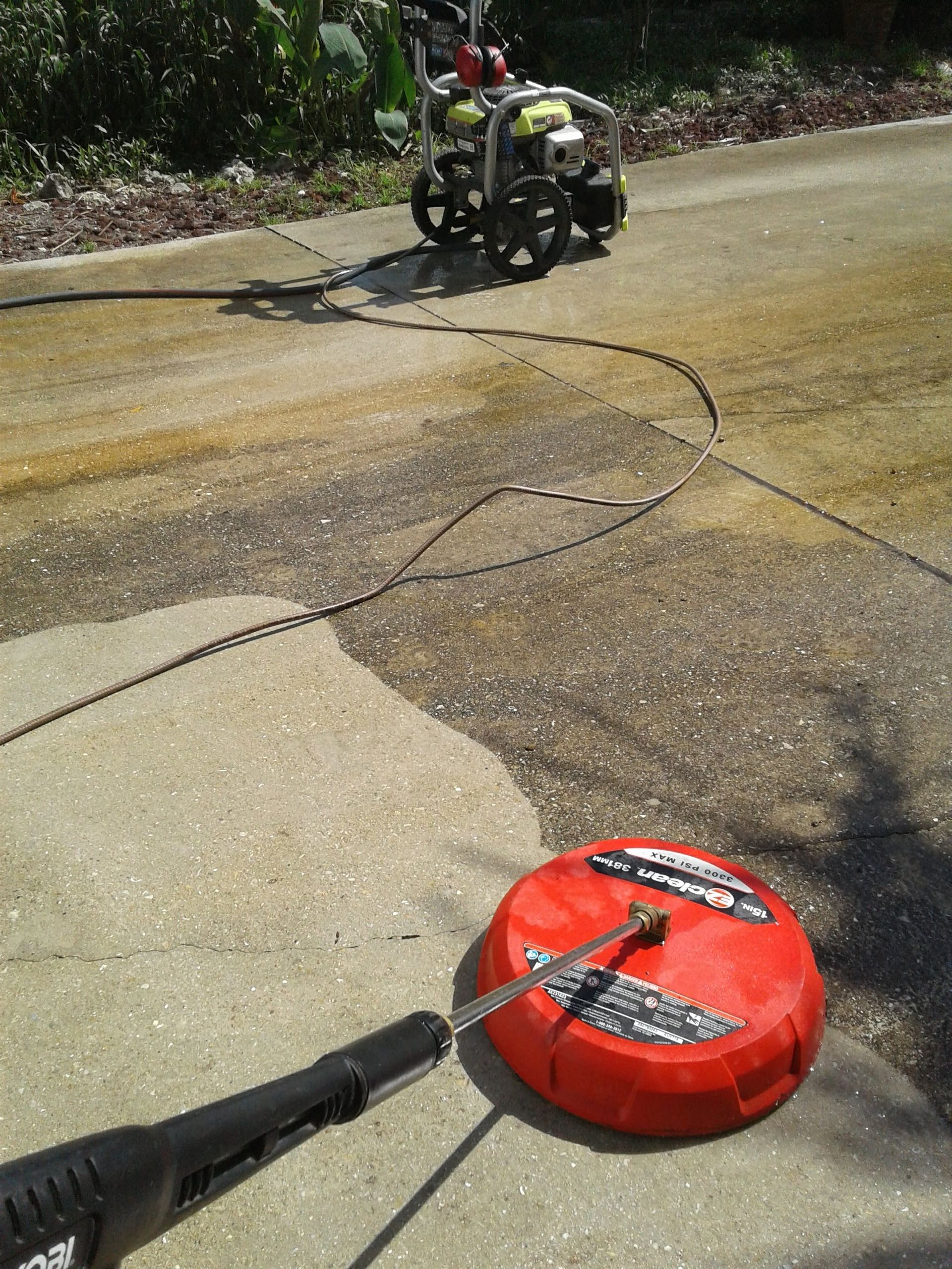 A pressure washer spraying water onto a concrete surface, creating a cleaner path.