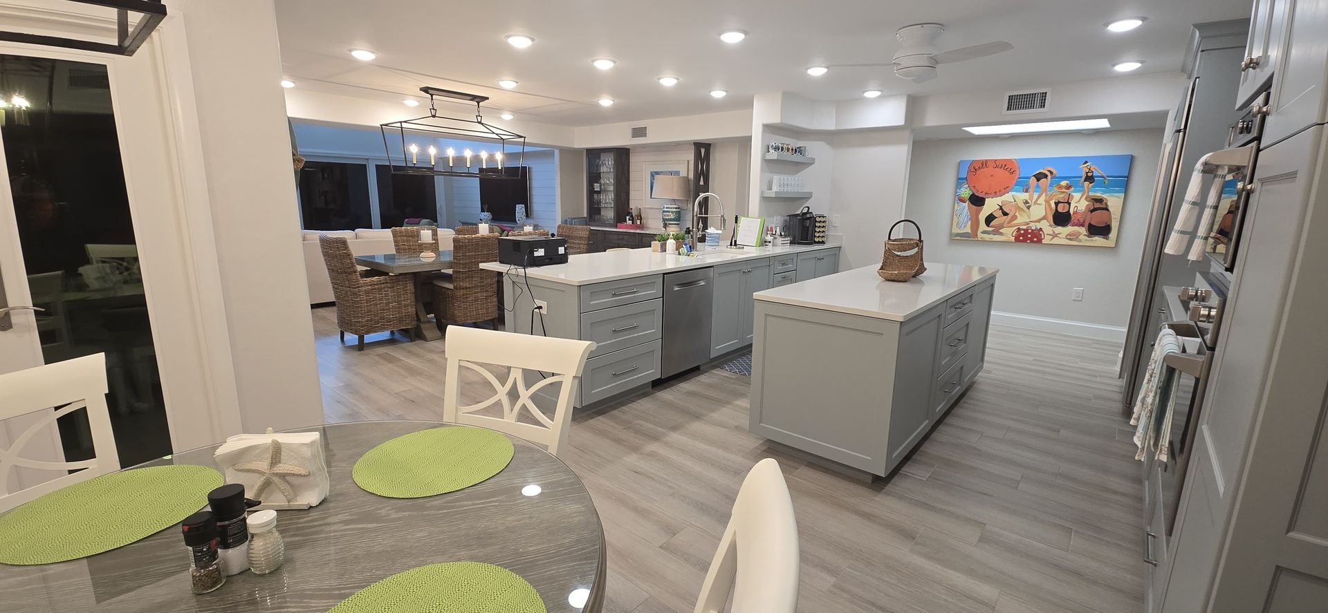 Blonde woman in gloves and apron, arms akimbo, in a messy kitchen.