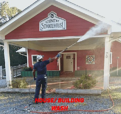A person power-washing a red building labeled 