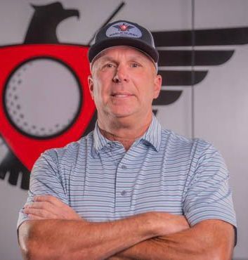 A man wearing a hat and a striped shirt is standing with his arms crossed.