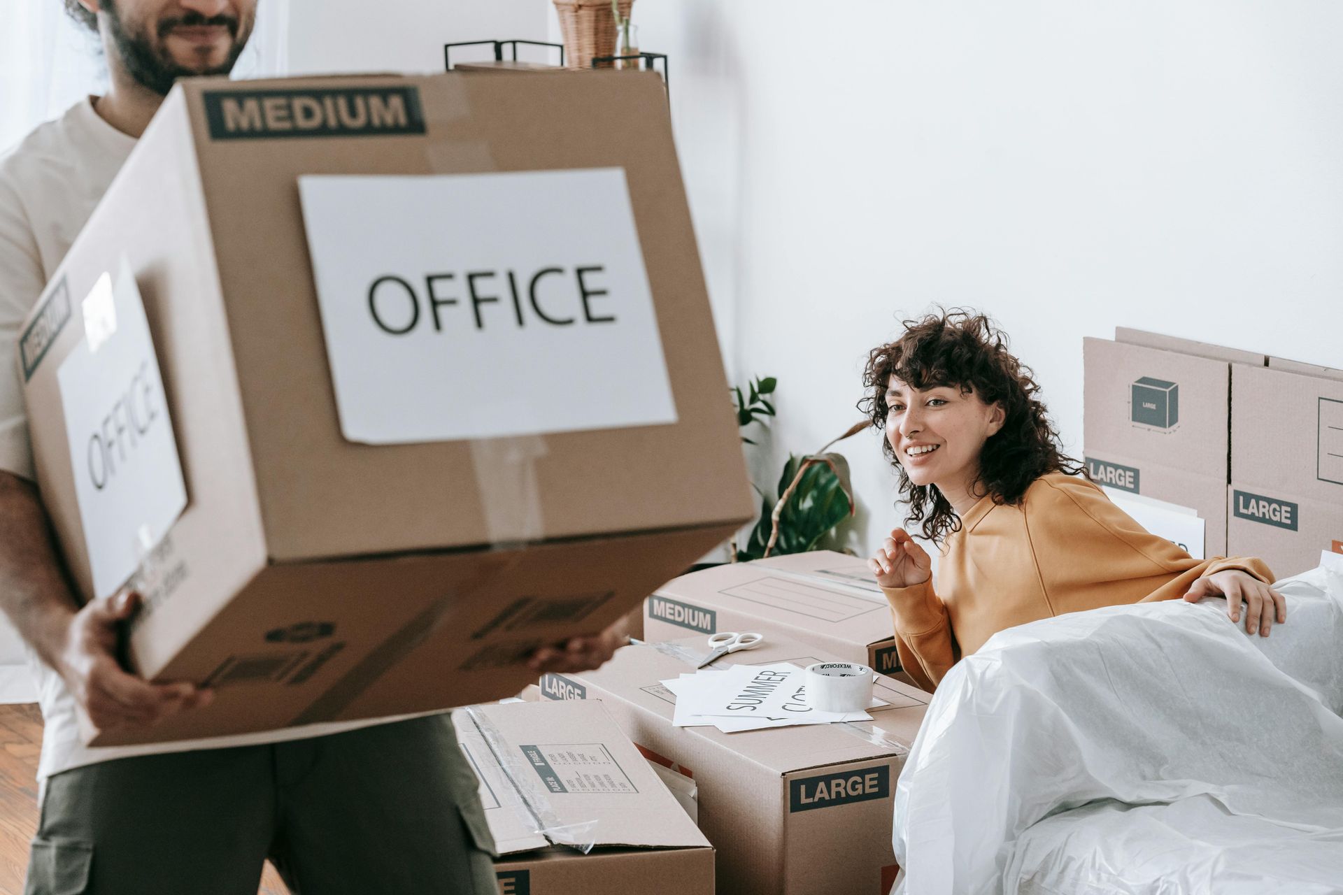 A man is carrying a box with the word office on it.