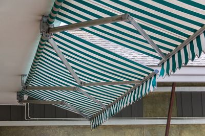 Green and white striped awning with asphalt roof background