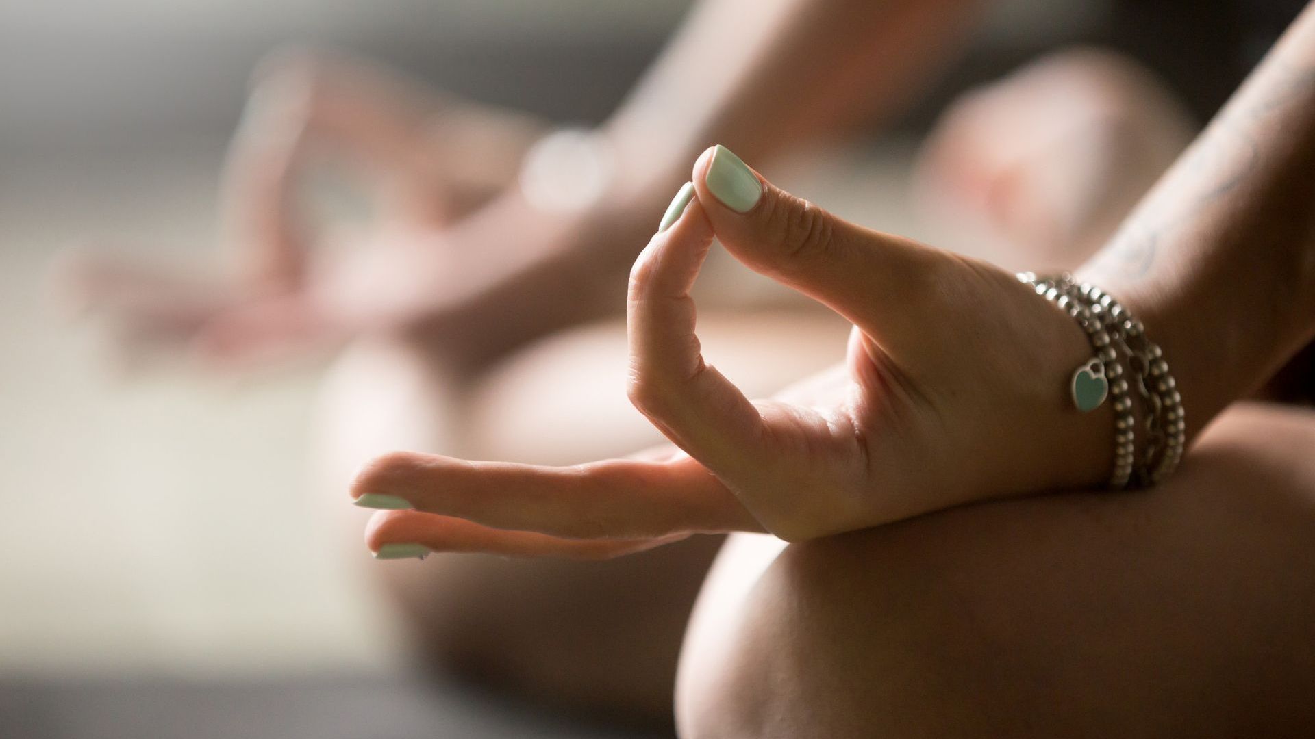 una mujer se sienta en una pose de yoga con los dedos cruzados