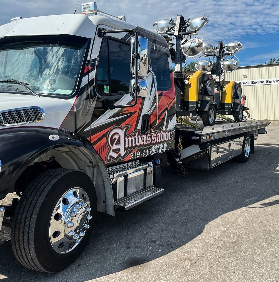 Tow truck with large lights on flatbed, black, white, and red design, Ambassador logo.
