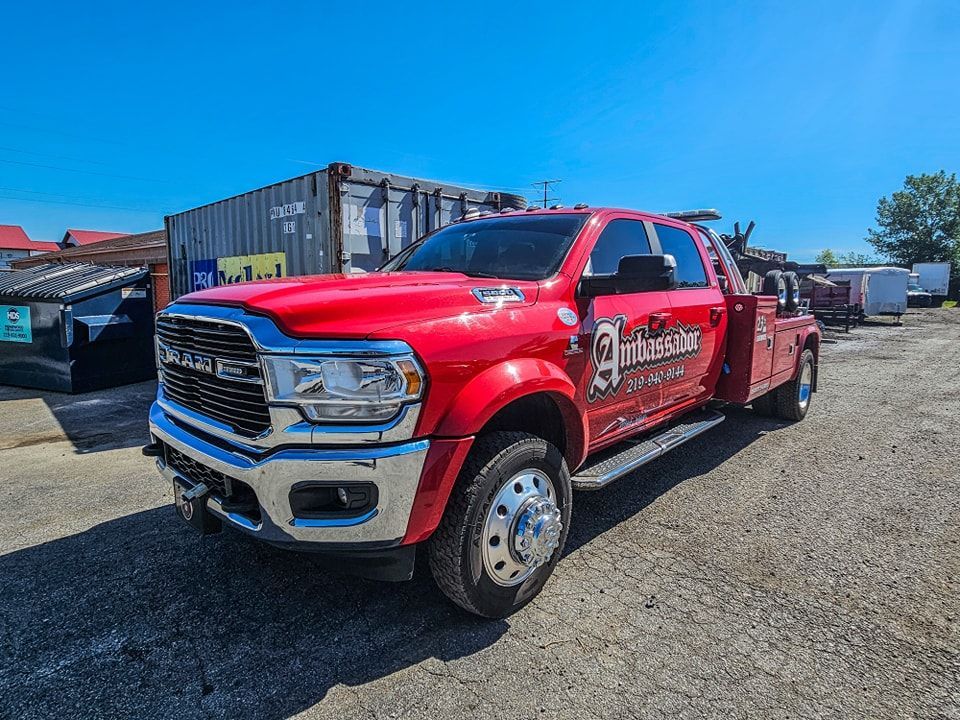 Red tow truck parked on gravel in a sunny outdoor setting.