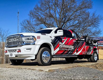White and red Ambassador tow truck parked outside on a sunny day.