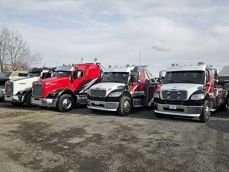 Several tow trucks parked outside on a cloudy day.