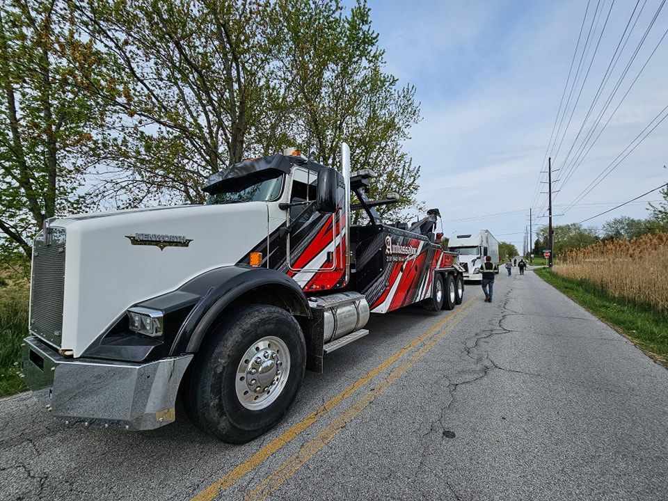 Tow truck with red accents towing a trailer on a rural road.