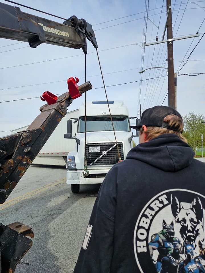 Tow truck hoisting a white semi-truck. A person with a 