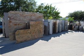 A row of granite slabs are stacked on top of each other in a yard.