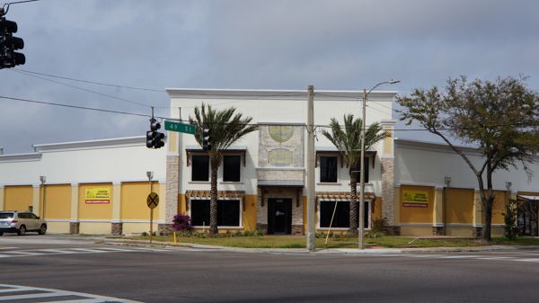 A white building with yellow doors is sitting on the corner of a street.