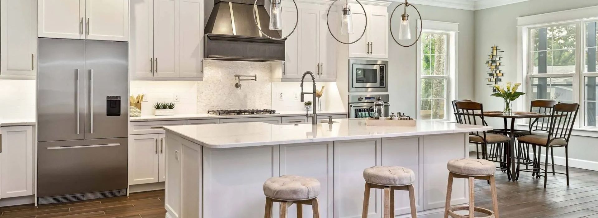 A kitchen with white cabinets and stainless steel appliances and a large island.