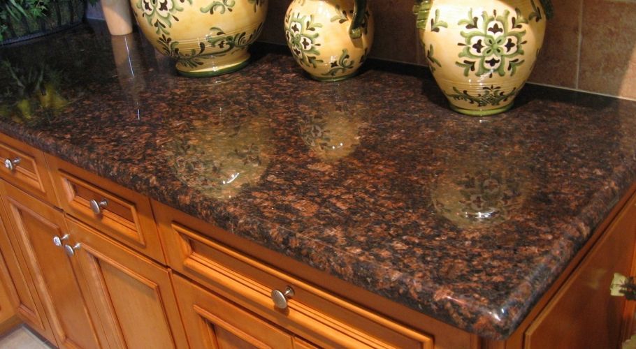 A brown granite counter top with three vases on it