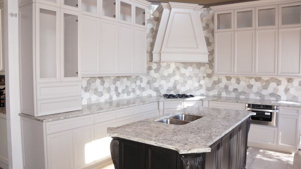 A kitchen with white cabinets , granite counter tops , and a large island.