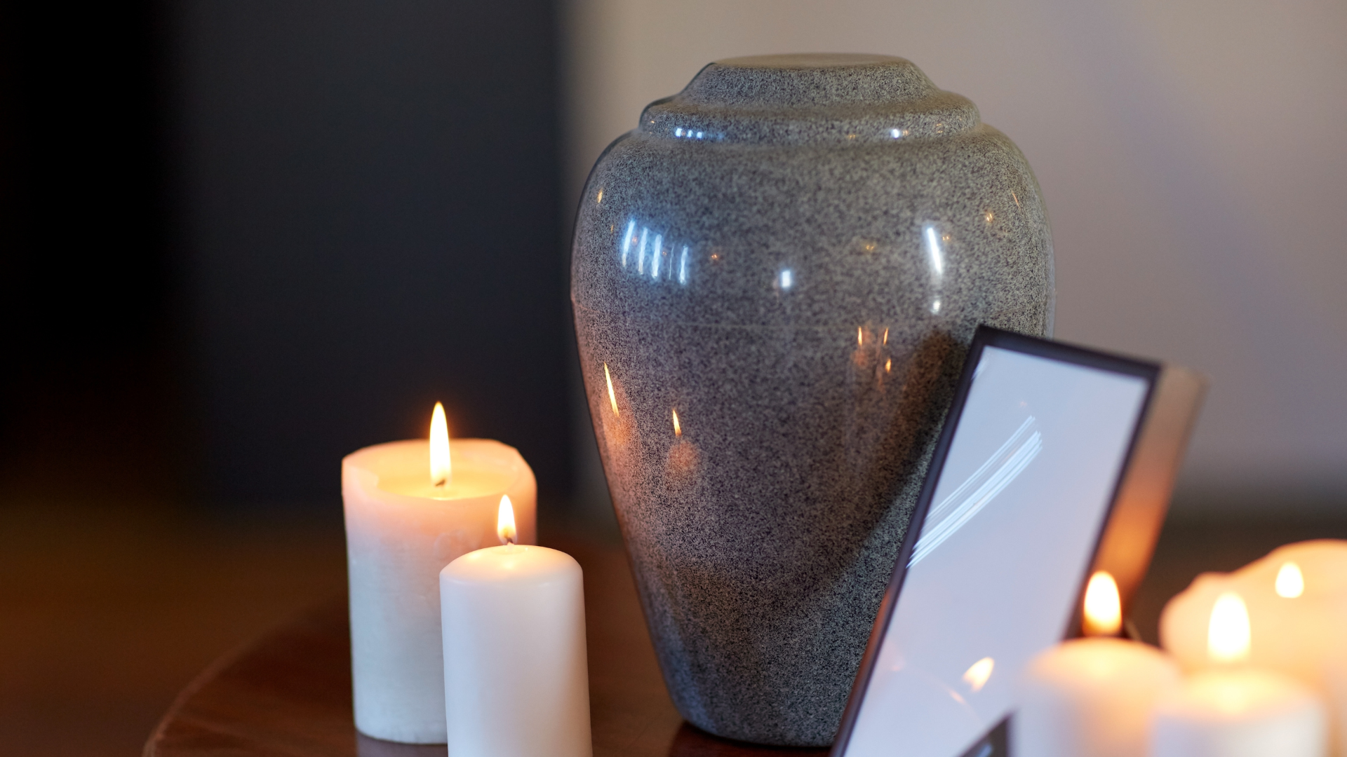 A vase sitting on top of a wooden table next to candles and a picture frame.