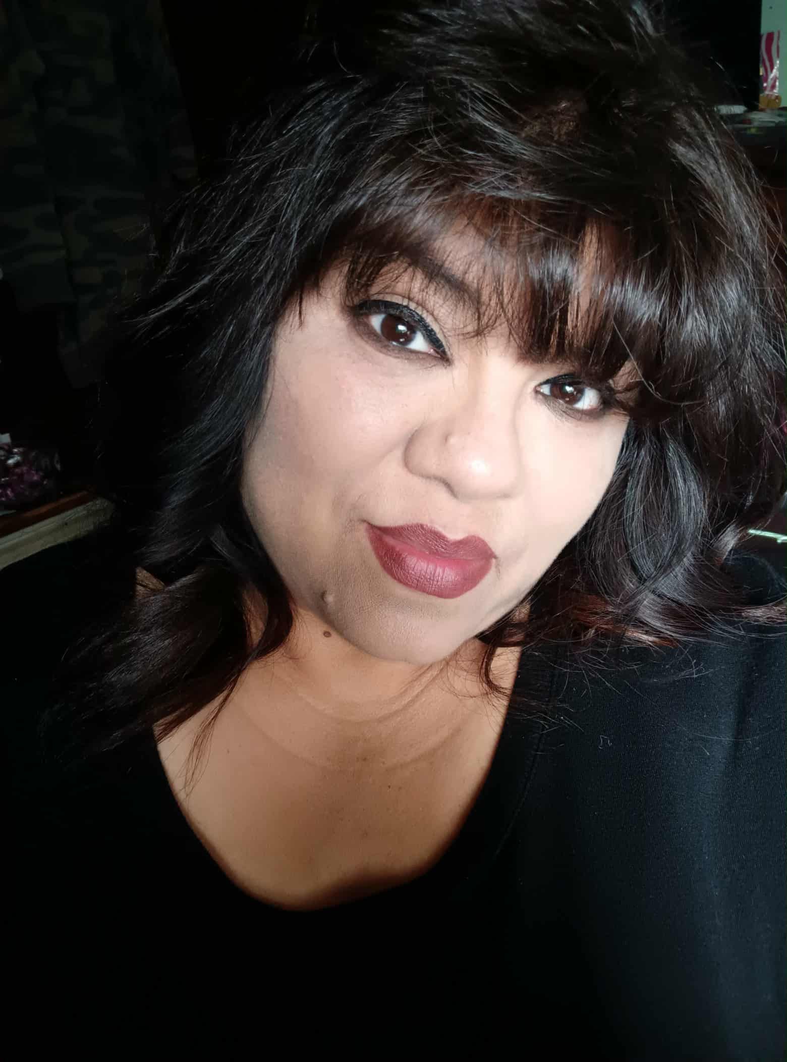 Woman with dark hair, red lipstick, looking at the camera.