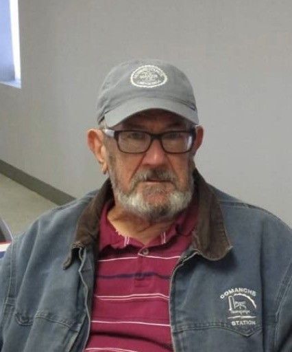 Man wearing glasses, a baseball cap, and a denim jacket, looking at the camera.