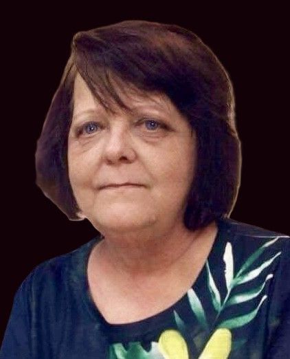 Woman with short brown hair, wearing a patterned top, looking forward.