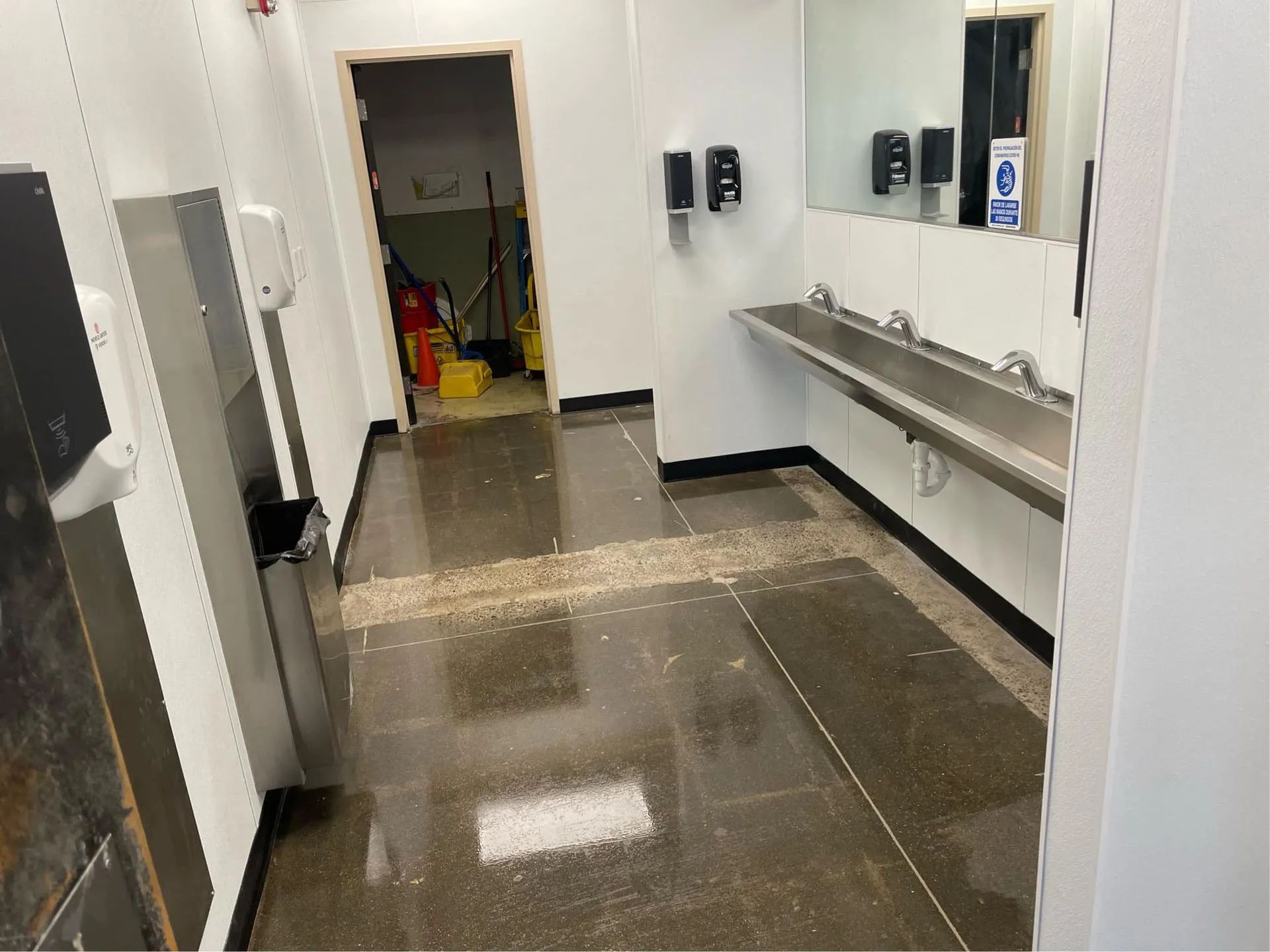 A bathroom with stainless steel sinks and a mirror.