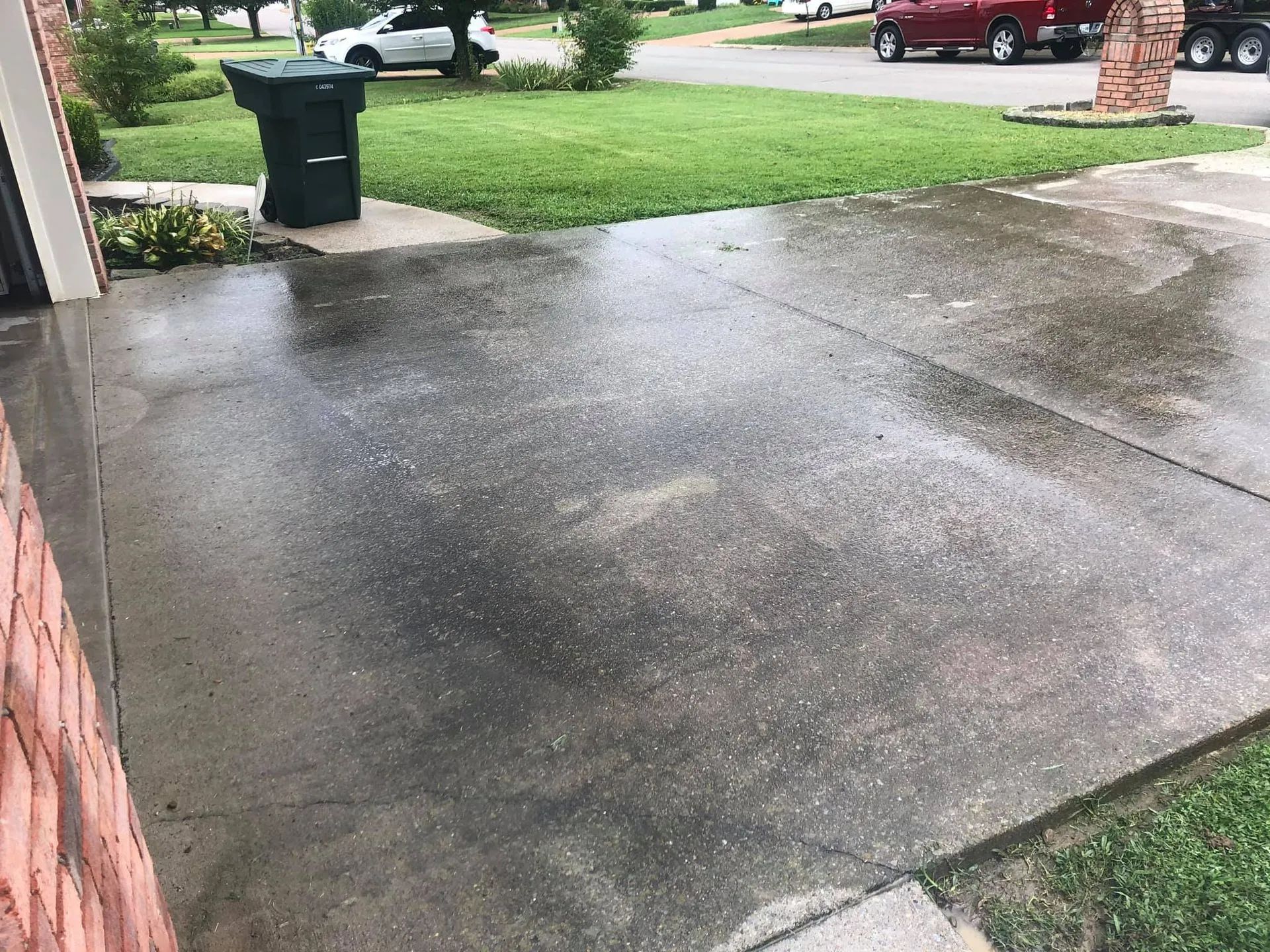 A dirty concrete driveway with a trash can in the middle of it.