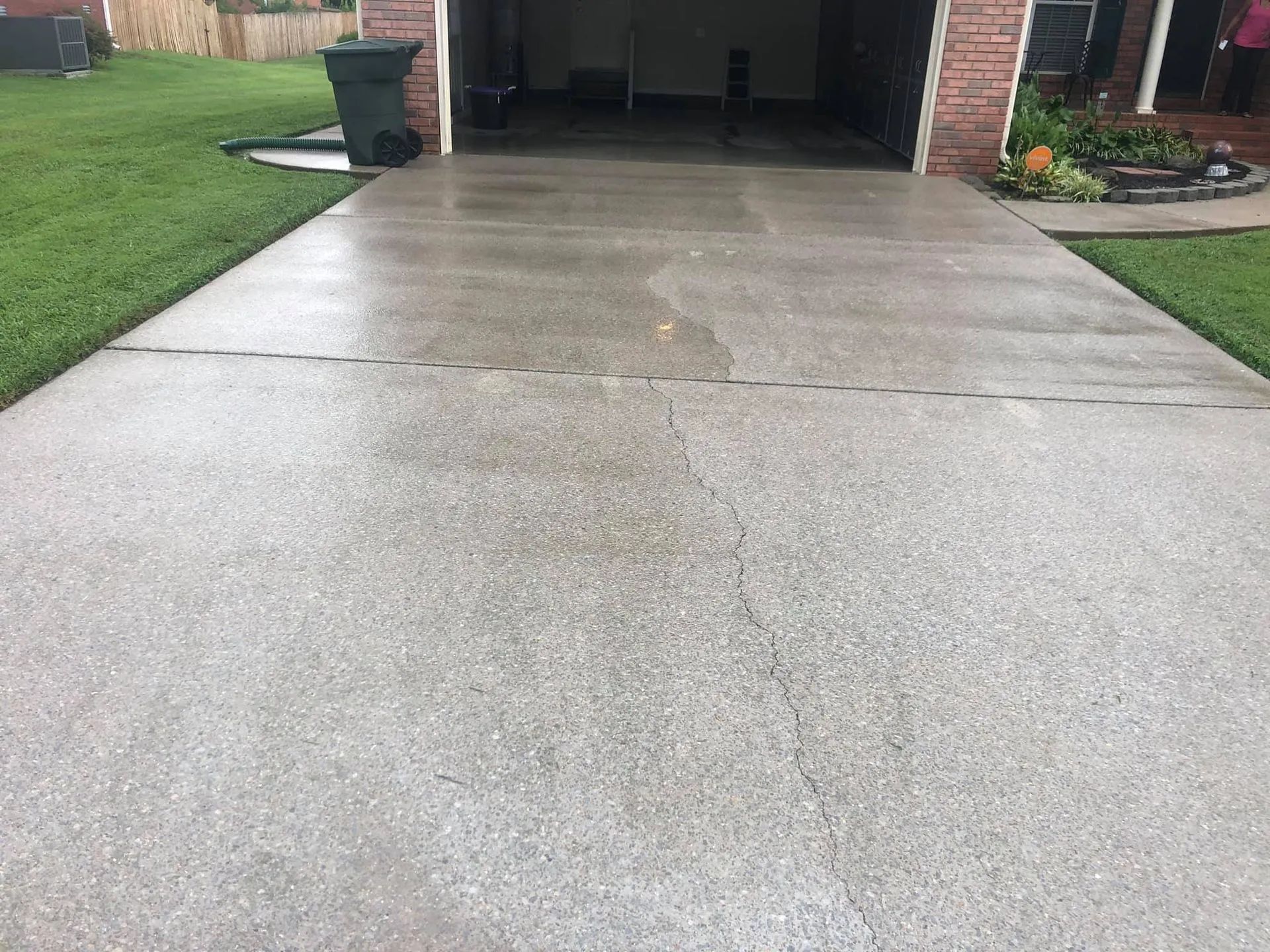 A concrete driveway leading to a garage next to a brick house.