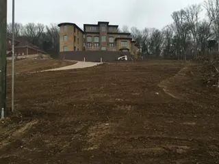 A large building is sitting on top of a dirt hill.