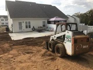 A small bulldozer is sitting in the dirt in front of a house.