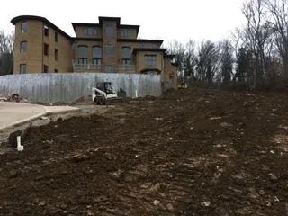 A bobcat is moving dirt in front of a large building.