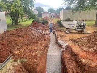 A man is standing in a trench next to a dump truck.